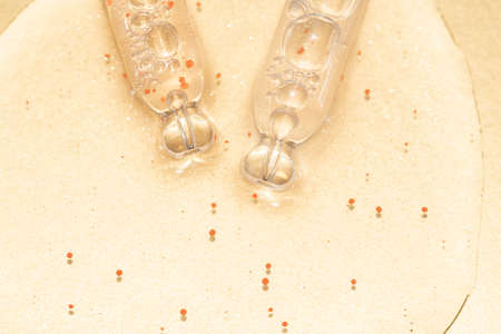 close up macro of two pipette droppers with liquid with particles on a gold background luxury serum conceptの写真素材