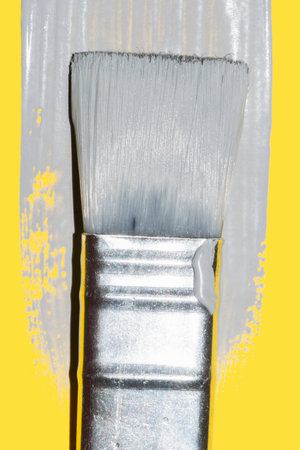 paint brush with fresh ultimate gray paint on illuminating yellow background 2021 color trend