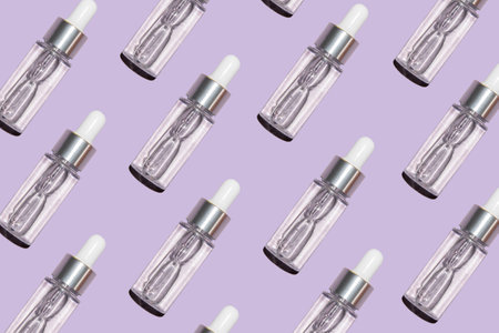 pattern of bottles with beauty serum on a purple background with selective focus top viewの写真素材