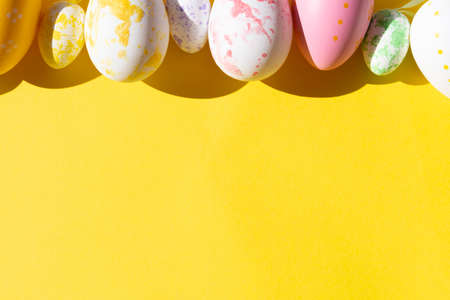 colorful painted easter eggs on yellow background festive easter card for your project with copy spaceの写真素材