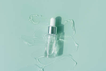 close up macro of pipette dropper bottle with liquid serum on a mint blue background luxury serum conceptの写真素材