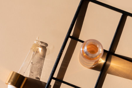 close up of pipette dropper with face serum with bottle and black metal grid on a beige backgroundの写真素材