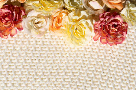 border colorful artificial flowers on a textured beige sweater background for your summer project