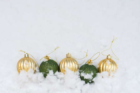 Gold and green Christmas baubles in white snow festive xmas background.の写真素材