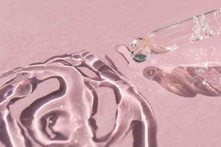 close up of a pipette dropper with pouring face serum on a pink background for your beauty project
