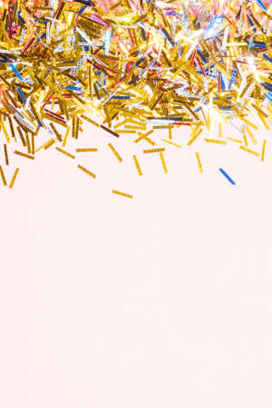 colorful tinsel confetti on a pink background for a festive christmas project