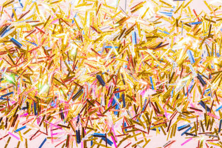 colorful tinsel confetti on a pink background for a festive christmas projectの写真素材