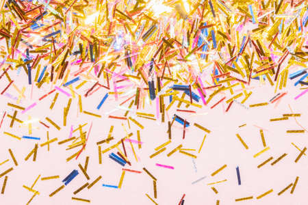 colorful tinsel confetti on a pink background for a festive christmas projectの写真素材