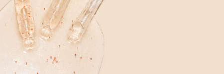 banner close up macro of pipette droppers with liquid with particles on a beige background luxury serum conceptの写真素材