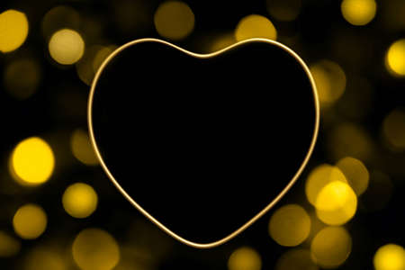 3d render of golden metallic heart frame with gold bokeh lights on a black backgroundの写真素材