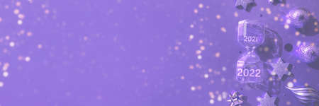 Luxurious violet Christmas flat lay of various ornaments and hourglass with the new year 2022 banner...