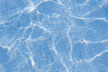 sun flare in beautiful blue swimming pool water with visible tiles