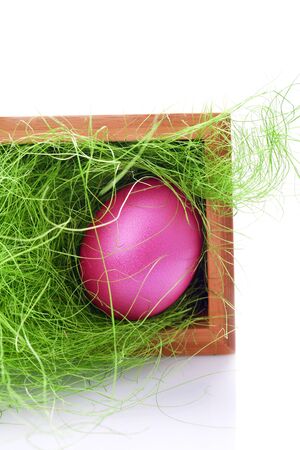pink easter egg in a basket with green grasの写真素材