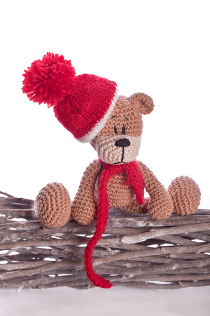 teddy bear with red hat and scarf on wooden branchの写真素材
