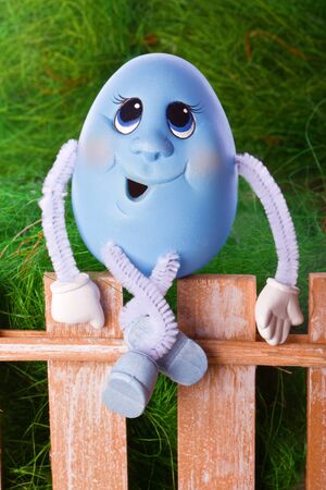 blue egg sits on a brown fenceの写真素材