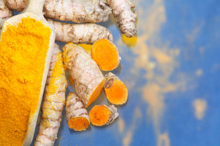 Turmeric powder (turmeric) in a wooden spoon and rootsの写真素材