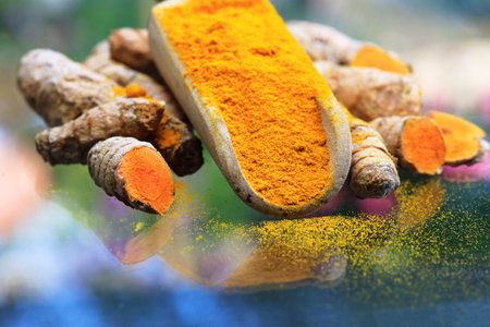 Turmeric powder (turmeric) in a wooden spoon and rootsの写真素材