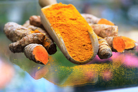 Turmeric powder (turmeric) in a wooden spoon and rootsの写真素材