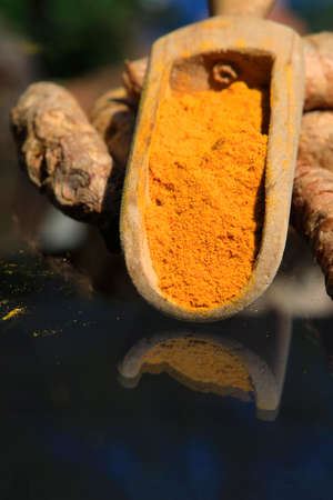 Turmeric powder (turmeric) in a wooden spoon and rootsの写真素材