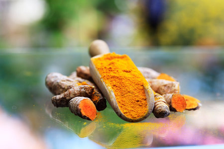 Turmeric powder (turmeric) in a wooden spoon and rootsの写真素材