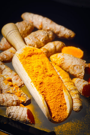Turmeric powder with fresh turmeric roots on a black background.の写真素材