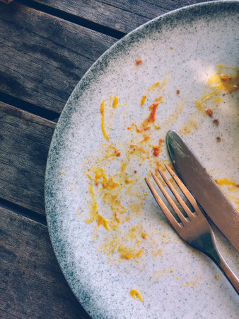 Dirty plate and cutlery on wooden table, top viewの写真素材