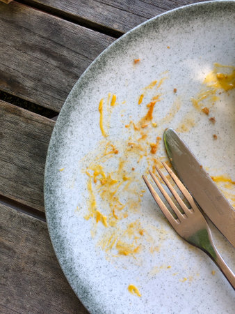 Dirty plate with fork and knife on wooden table, top viewの写真素材