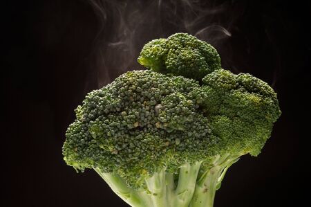 Close up on broccoli with  steam on black backgroundの写真素材