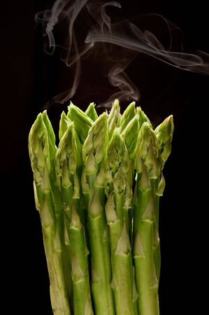 asparagus bunch with steam on black backgroundの写真素材