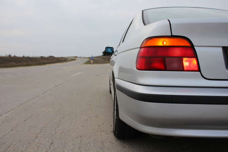 Car with hazard warning flashers is waiting on roadside