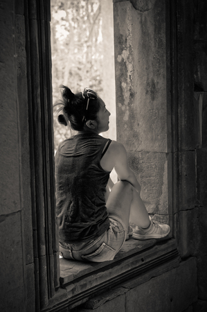 Siem Reap, Cambodia: An asian girl is sitting in a windowのeditorial素材