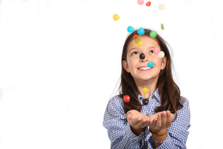 Young girl catching candies falling from the sky on a white backgroundの写真素材