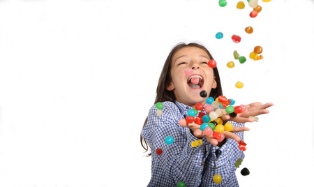 Young girl catching candies falling from the sky on a white backgroundの写真素材