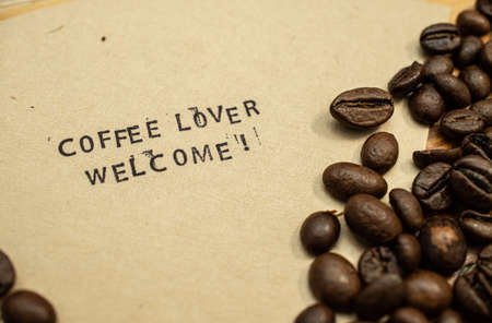 Coffee lover welcome stamped on coffee filter with coffee beans on wood tableの写真素材