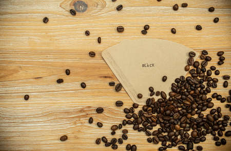 black coffee letters stamped on brown filter with espresso beans on wood table