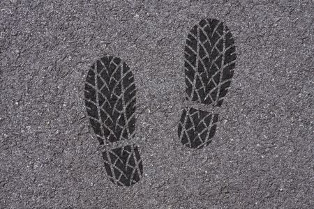 Footprint of shoes with tire tread pattern on asphalt backgroundの写真素材