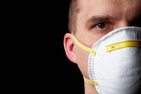 close up of a young man wearing a protective mask in dark atmosphereの写真素材