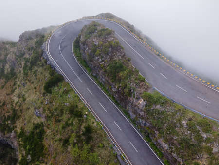 A drone shot of an empty mountain road above the clouds in Madeira Island, Portugalの写真素材