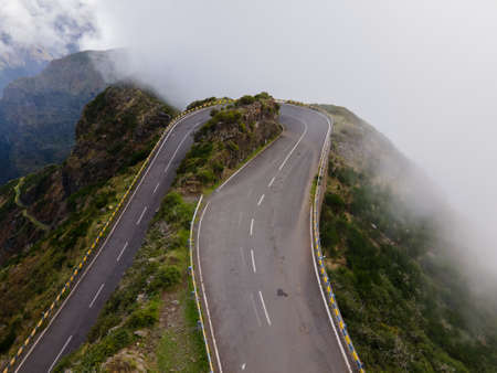 A drone shot of an empty mountain road above the clouds in Madeira Island, Portugalの写真素材