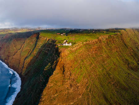 The cliff lighthouse Ponta do Pargo on the cliff coast of the Island of Madeira - Wonderful cloudy cliff landscapeの写真素材