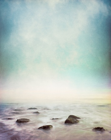 Mist and fog rising from a rocky ocean shore.  Image has a vintage paper texture and displays a pleasing grain pattern at 100%.の写真素材