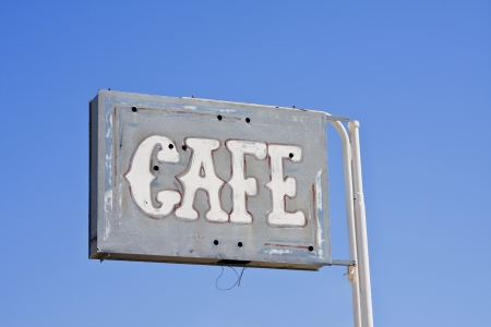 An old and weathered restaurant sign displaying the location of an abandoned cafe in the Mojave desert の写真素材
