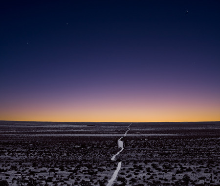 A lonely and empty Mojave desert road just after sunset.の写真素材