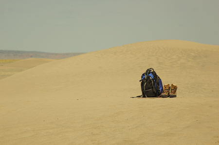 Lonely backpack and hiking boots in the desertの写真素材