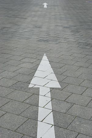 White  straight Arrows on the grey road