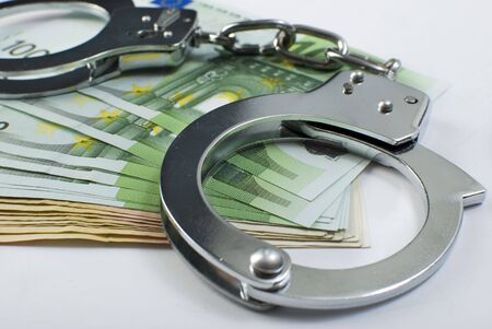 Close-up handcuffs and money over white background. Not isolated.の写真素材