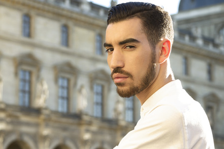 Street fashion concept. Portrait of elegant young handsome man. Paris buildings as background.