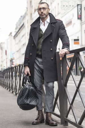 Street fashion concept. Portrait of elegant young handsome man. Paris buildings as background.の写真素材