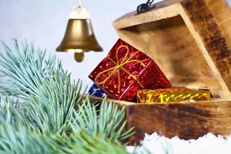 Christmas gift in red packaging. Christmas decoration for Christmas greeting with a chest, a branch of white pine and an inherent bell.の写真素材