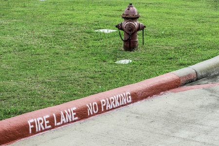 A side angle shot of a curb reading "Fire Lane" and a hydrant behind it.の写真素材